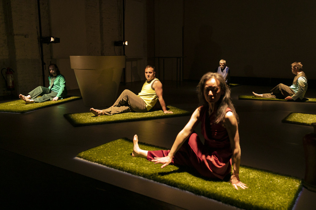 Szenenfoto aus einer Aufuehrung: Fünf Personen sitzend auf einer Theaterbühne.