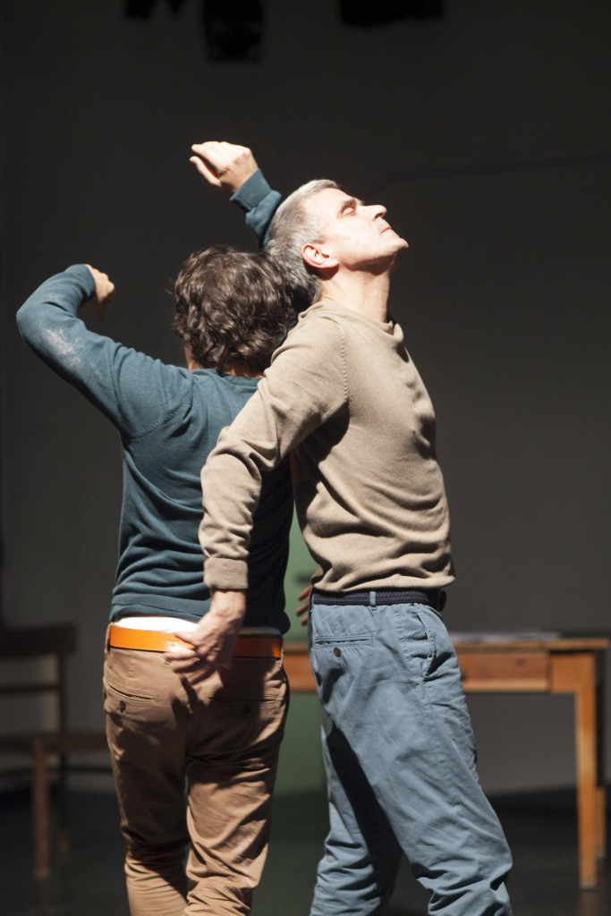 Scene photo of a performance: Two men back to back on a stage.