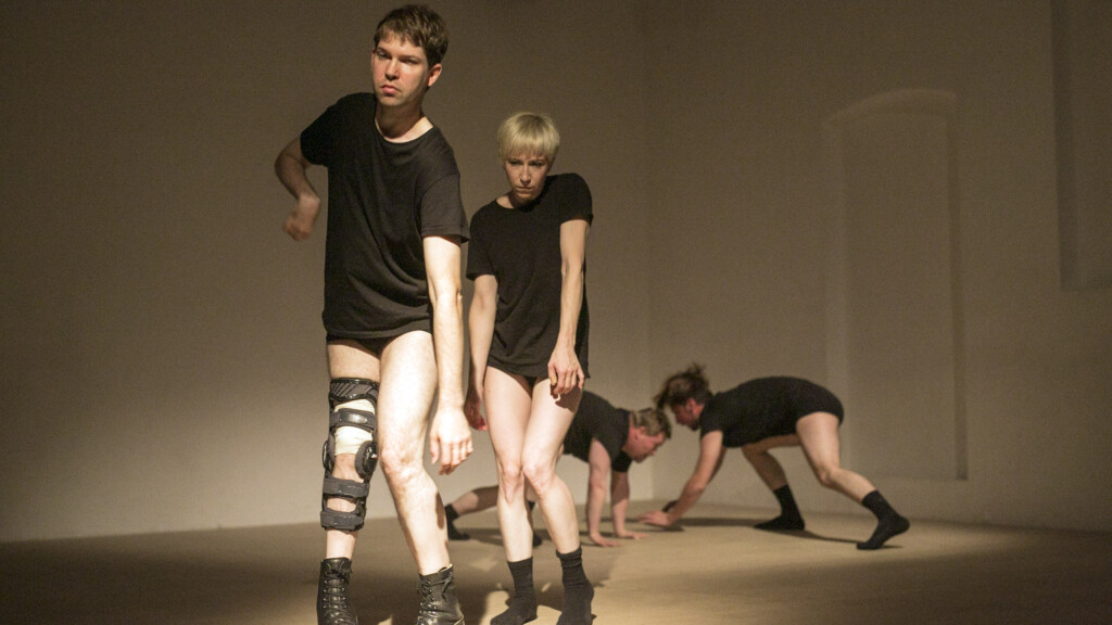 Scene photo of a performance: Four people on a stage. Two in the foreground. Two in the background.