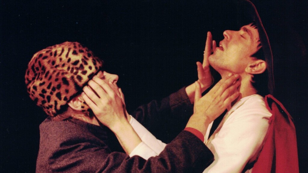 Scene photo of a performance: One woman and a men on a stage touching each others face.