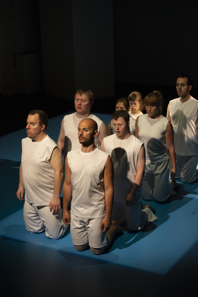 Scene photo of a performance: A couple of people keeling being each other on a stage.