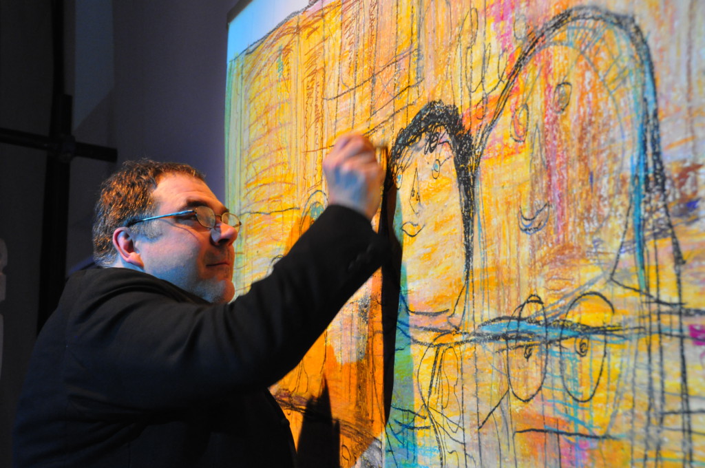 Photo from a performance: One man in front of a canvas on a stage.