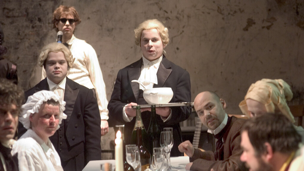 Scene photo of a performance: 8 people on a celebration table on a stage.