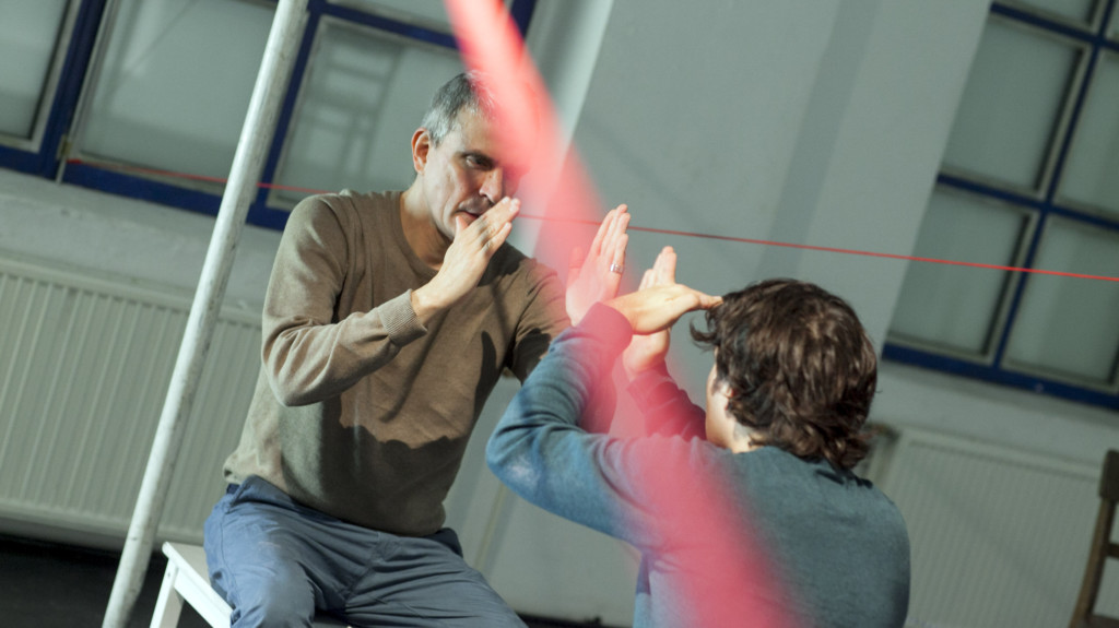 Scene photo of a performance: Two men sitting in front of each other on a stage.
