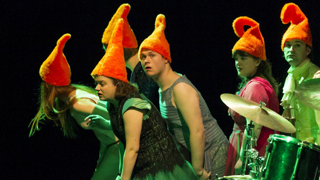Scene photo of a performance: A couple of people with dwarf hats on a stage.