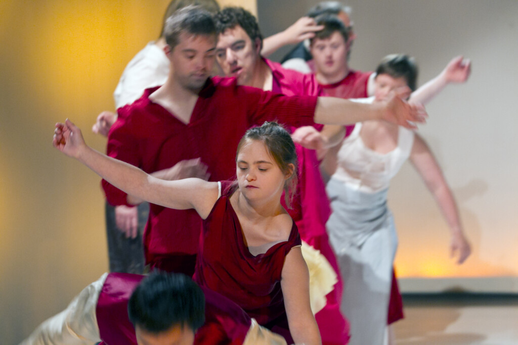 Szenenfoto einer Auffuehrung: mehrere tanzende Menschen auf einer Buehne hintereinander