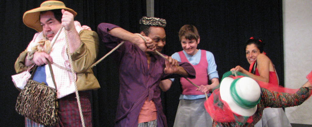 Szenenfoto einer Auffuehrung: Vier Personen nebeneinander auf einer Bühne