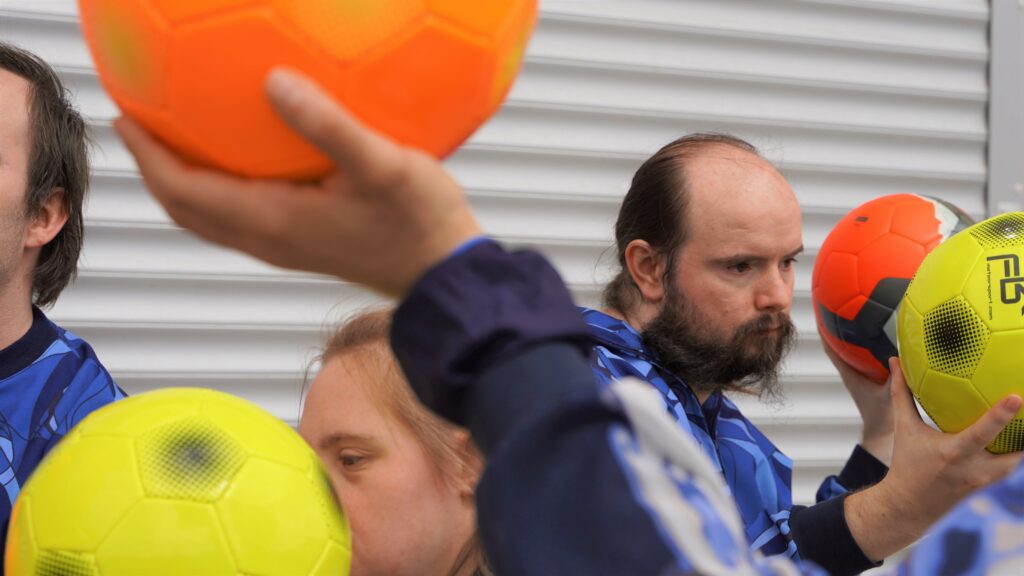 Three people are holding yellow and orange balls.