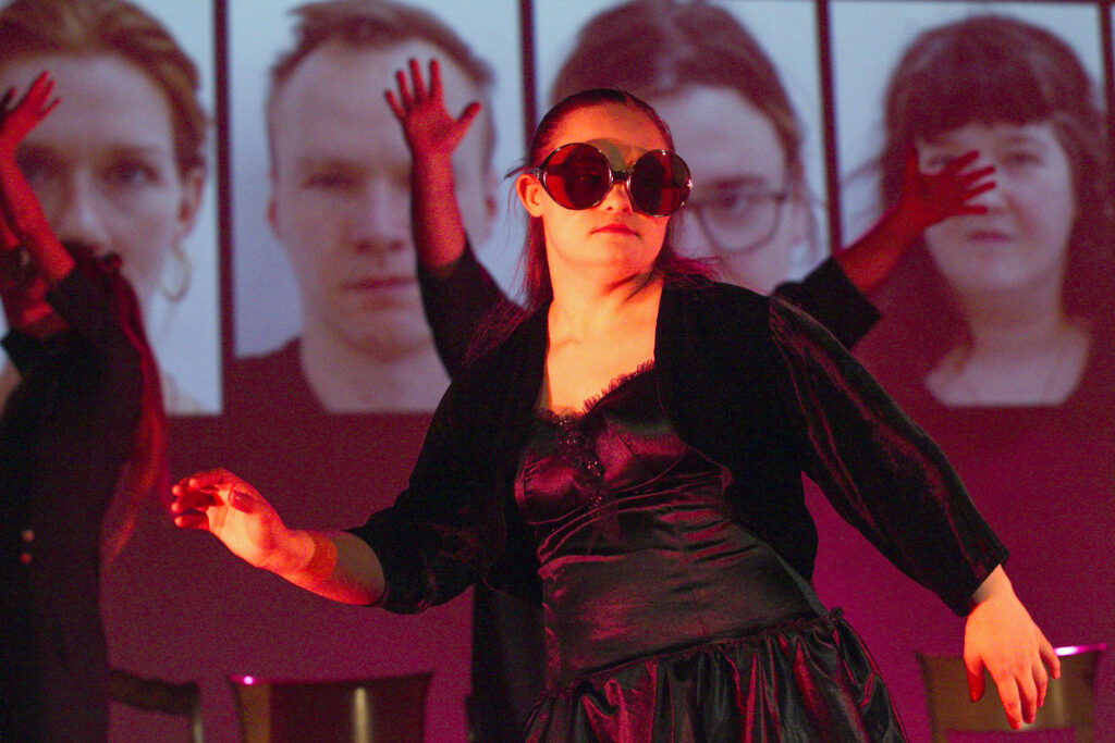 Scene photo of a performance: A person with big round sun glasses who is dancing.