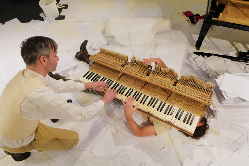 Eine Klaviertastatur liegt auf einem Menschen. Eine andere Person spielt auf der Tastatur.